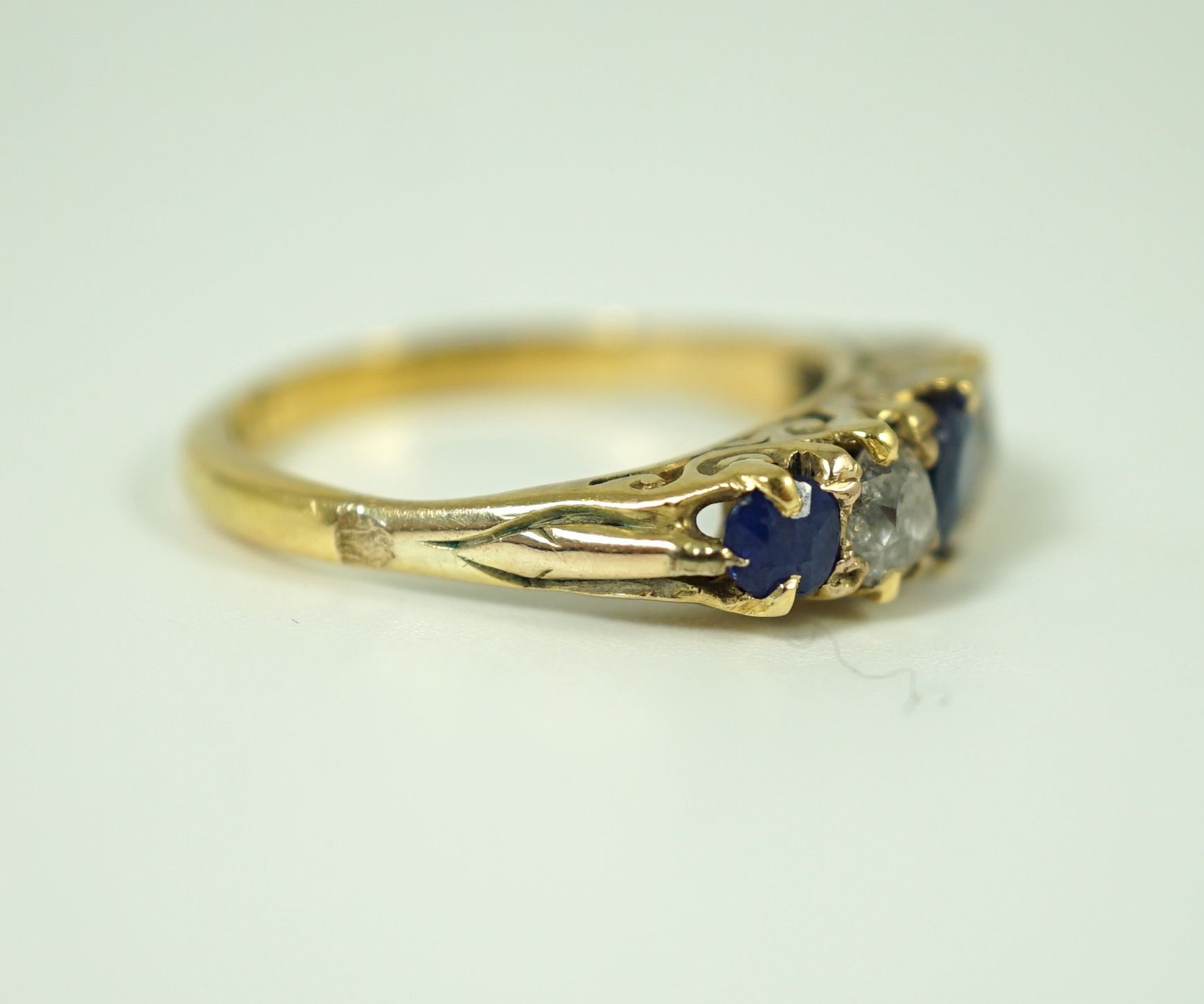 An 18ct gold, graduated three stone sapphire and two stone diamond set half hoop ring